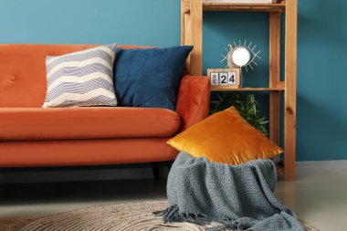 Oturma odasının içinde turuncu kanepe, yastıklar ve raflarda küçük bir ayna var.