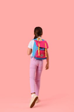 Pembe arka planda sırt çantası olan küçük bir kız.