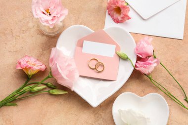 Zarflı kompozisyon, boş kart, alyans ve bej arka planda östoma çiçekleri, yakın plan.