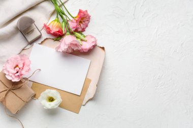 Boş kartlı kompozisyon, alyans ve açık arkaplanda östoma çiçekleri
