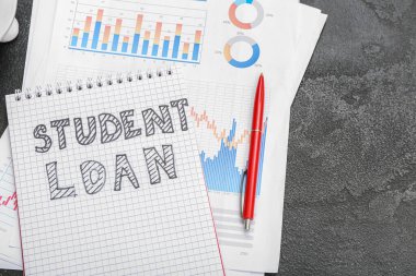 Siyah arkaplan üzerinde SÜDENT kredisi, kalem ve çizelgeleri olan defter