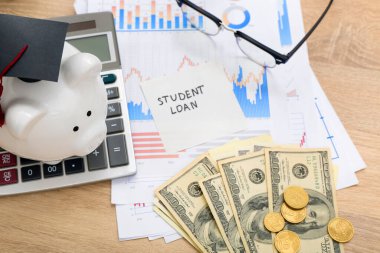 Metin ÖĞRETMENLERİ, dolar banknotları ve ahşap arka planda domuz kumbarası olan yapışkan bir not.