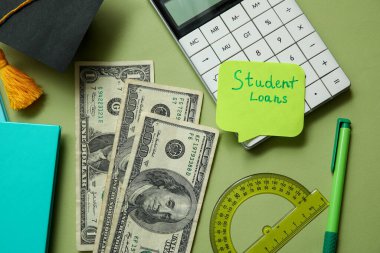 SMS kredileri, mezuniyet şapkası, dolar banknotları, yeşil arkaplanda hesap makinesi ve kırtasiye malzemesi olan yapışkan bir not.