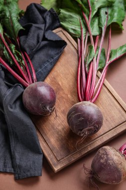 Kahverengi arka planda taze pancar kökleri olan kesme tahtası