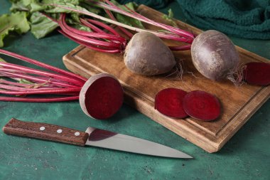 Taze kesilmiş pancar kökleri ve yeşil masada bıçak ile tahta kesmek.