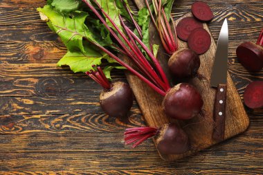 Tahta arka planda yeşil yapraklı taze pancar pancarları.
