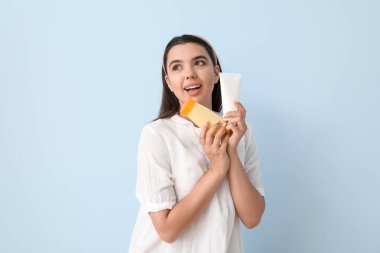 Işıklı arka planda güneş kremi şişeleri olan güzel genç bir kadın.