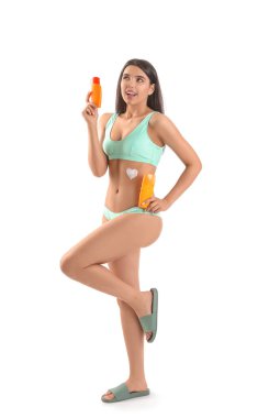 Beyaz arka planda güneş kremi şişeleri olan güzel genç bir kadın.