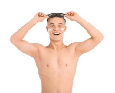 Yüzünde güneş kremi ve güneş gözlüğü olan mutlu genç bir adam.