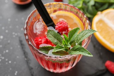 Siyah arkaplanlı bir bardak taze ahududu limonatası.