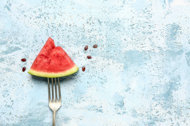 Taze karpuz parçalı çatal ve mavi arka planda tohumlar.