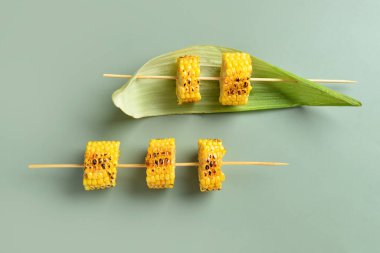 Yeşil arka planda lezzetli ızgara mısır koçanı şişleri.