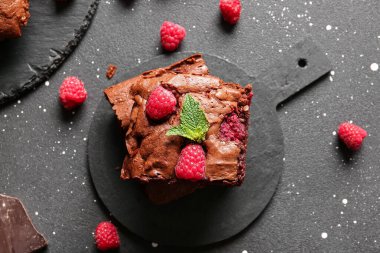 Siyah masanın üzerinde ahududulu çikolatalı browni var.