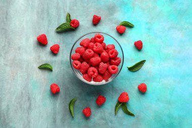 Mavi arka planda taze ahududu ve nane şekerli cam kase.