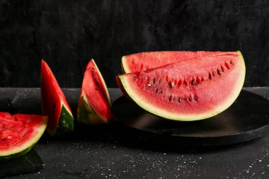 Siyah arka planda taze karpuz parçaları olan tahta.