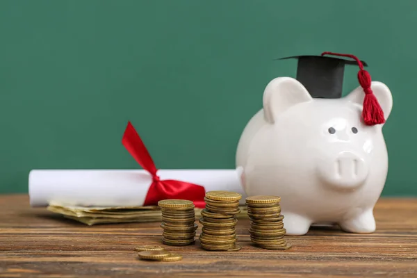 緑の背景に木製のテーブルの卒業キャップと卒業証書でコイン 貯金箱のスタック 学生ローンの概念 — ストック写真