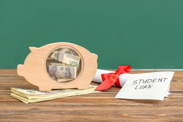 ピギーバンク ドル紙幣 卒業証書と付箋付きテキスト学生ローン緑の背景に木製のテーブルの上に — ストック写真