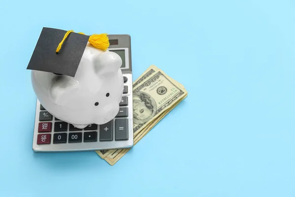 卒業キャップの貯金箱 青い背景の電卓とドル紙幣 学生ローンの概念 — ストック写真