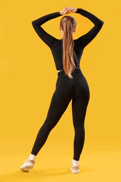 Sarı Arka Planda Spor Kıyafetli Genç Bir Kadın — Stok fotoğraf