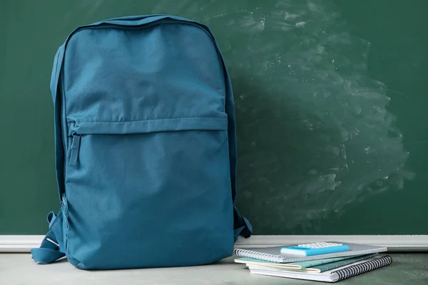蓝色学校背包 桌上有笔记本和计算器 接近绿色黑板 — 图库照片