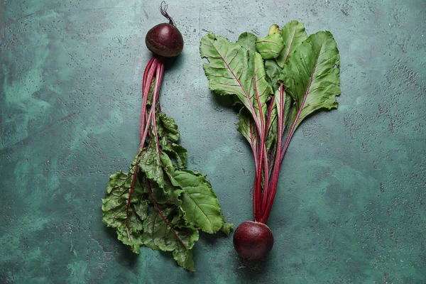 stock image Fresh beetroots with leaves on green table