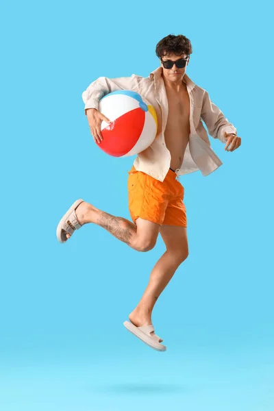 Giovane Uomo Con Palla Spiaggia Saltando Sfondo Blu — Foto Stock