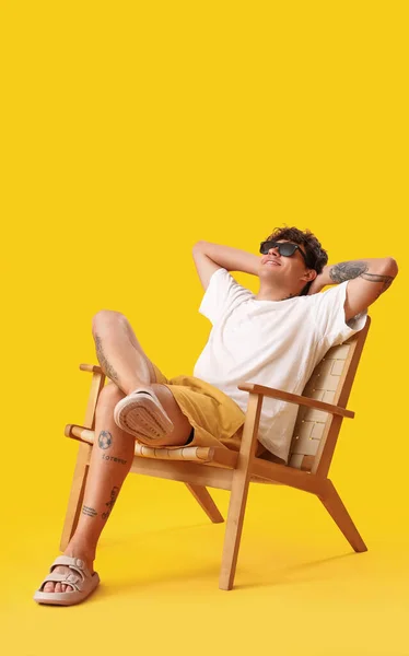 Jovem Descansando Cadeira Sobre Fundo Amarelo — Fotografia de Stock