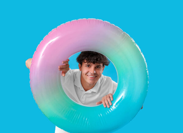 Молодой человек с плавающим кольцом на синем фоне