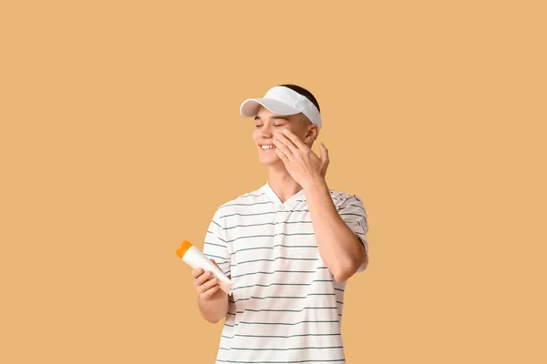 Gelukkig Jongeman Het Aanbrengen Van Zonnebrandcrème Oranje Achtergrond — Stockfoto