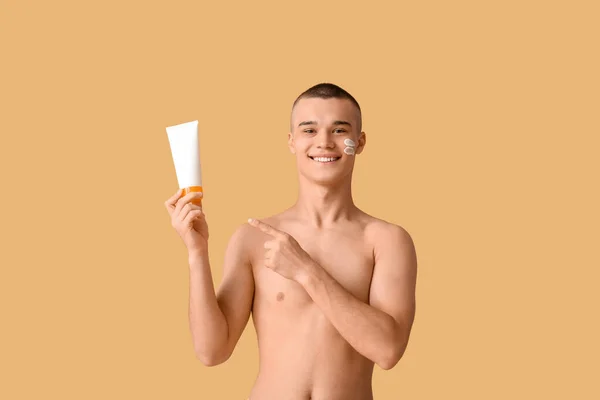 幸せな若い男指しているボトルの日焼け止めクリームでオレンジの背景 — ストック写真