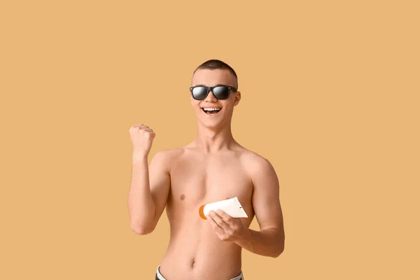 Щасливий Молодий Чоловік Сонцезахисних Окулярах Пляшкою Сонцезахисного Крему Помаранчевому Фоні — стокове фото