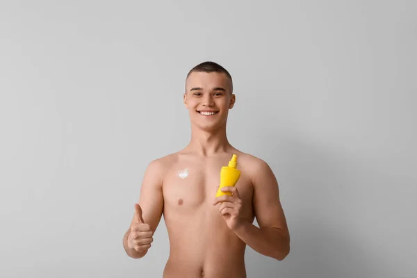 Happy Young Man Bottle Sunscreen Cream Showing Thumb Gesture Grey — Stock Photo, Image
