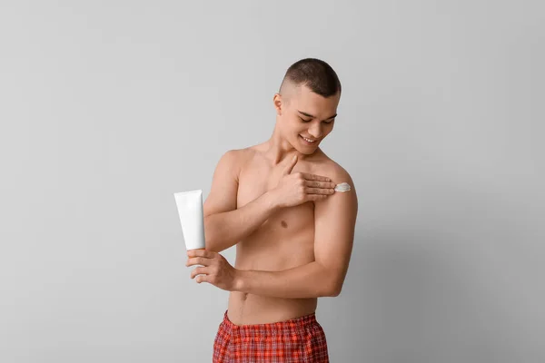 Happy Young Man Applying Sunscreen Cream His Body Grey Background — Stock Photo, Image