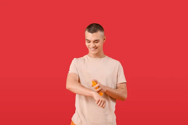 Happy Young Man Applying Sunscreen Cream His Body Red Background — Stock Photo, Image