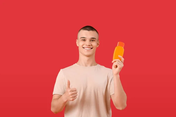 Happy Young Man Bottle Sunscreen Cream Showing Thumb Gesture Red — Stock Photo, Image