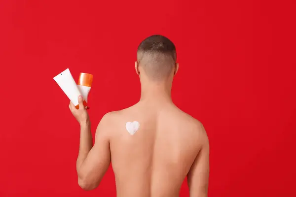 Young Man Bottles Sunscreen Cream Red Background Back View — Stock Photo, Image