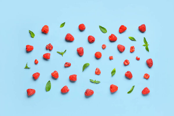 Many fresh raspberries and mint on blue background