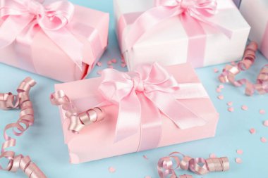 Mavi arka planda fiyonklu hediye kutuları, konfeti ve yılan yağı, yakın plan