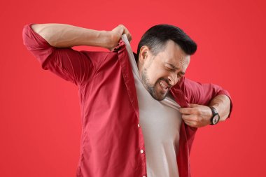 Genç adam kırmızı arka planda panik atak geçiriyor.