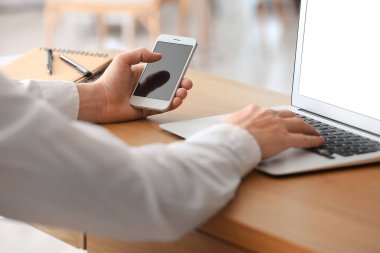 Akıllı telefon ve dizüstü bilgisayarı olan bir iş adamı, yakın plan.