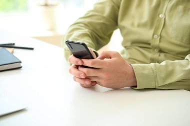 Sofrada akıllı telefonu olan adam, yakın plan.