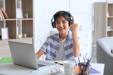 Kulaklıklı küçük çocuk evde ders çalışıyor.