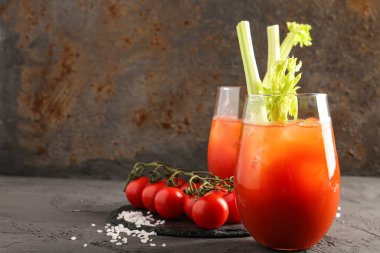 Gri masadaki domatesli ve kerevizli Bloody Mary bardakları
