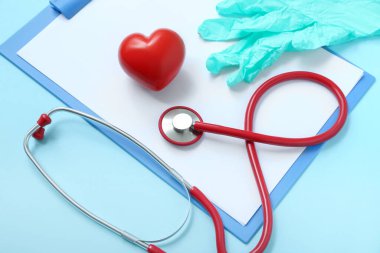 Not panosu, tıbbi eldivenler, steteskop ve mavi arka planda kalp.