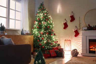 Noel ağacı hediyeler, parlayan ışıklar ve karanlık oturma odasında şömine.