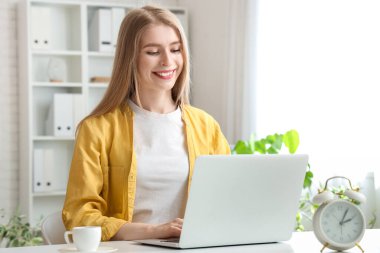 Ofiste dizüstü bilgisayarla çalışan genç bir iş kadını.