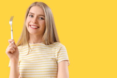 Sarı arka planda çatallı genç bir kadın.