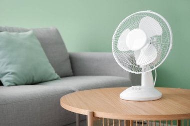 Oturma odasının içinde modern elektrikli vantilatör olan ahşap masa.