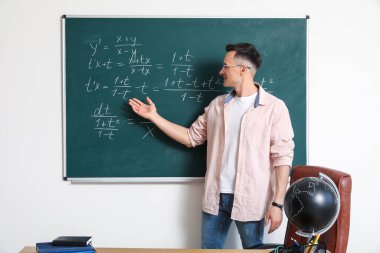 Sınıfta yazı tahtasının yanında erkek matematik öğretmeni