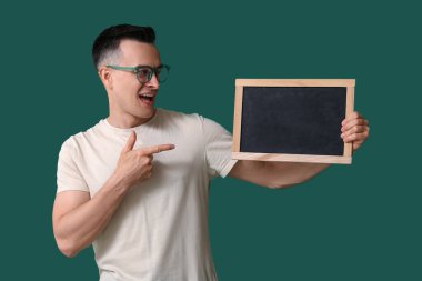 Yeşil arkaplanda tahtaya işaret eden erkek öğretmen